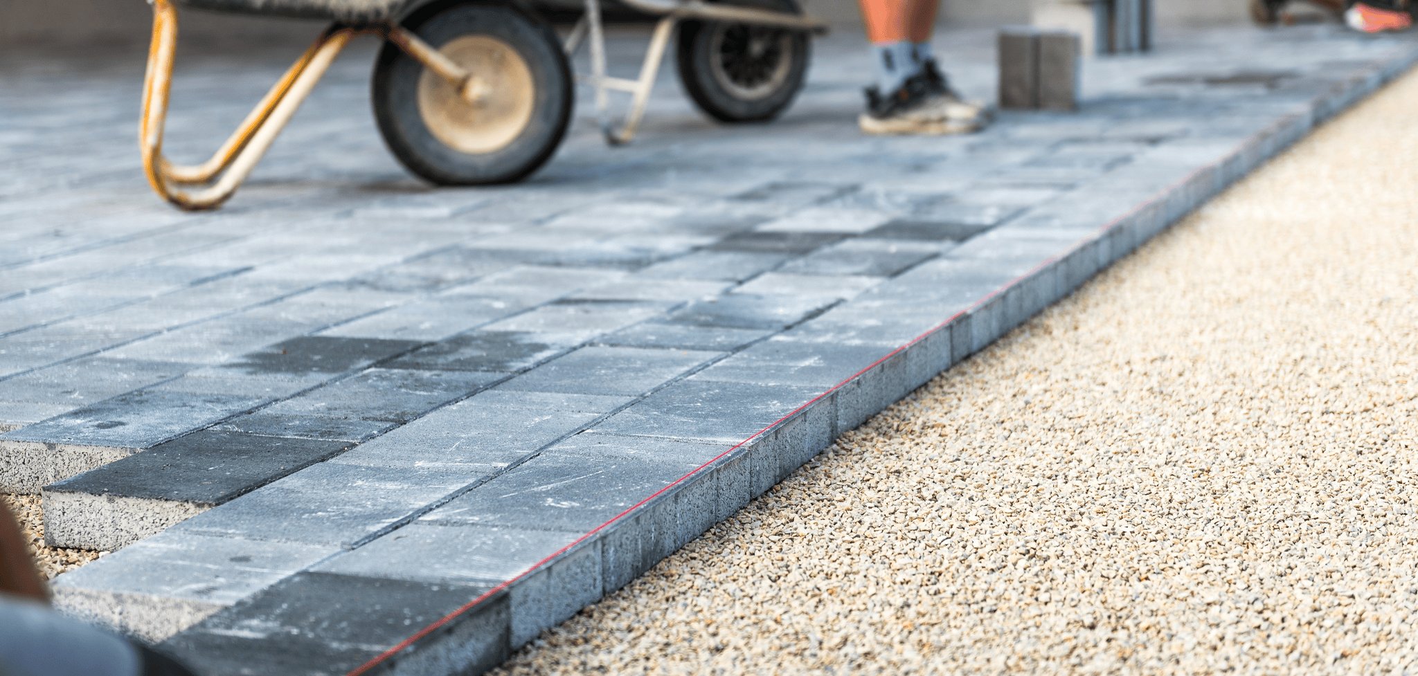Closeup of paver installation in progress with stone pavers being laid into sand bedding.