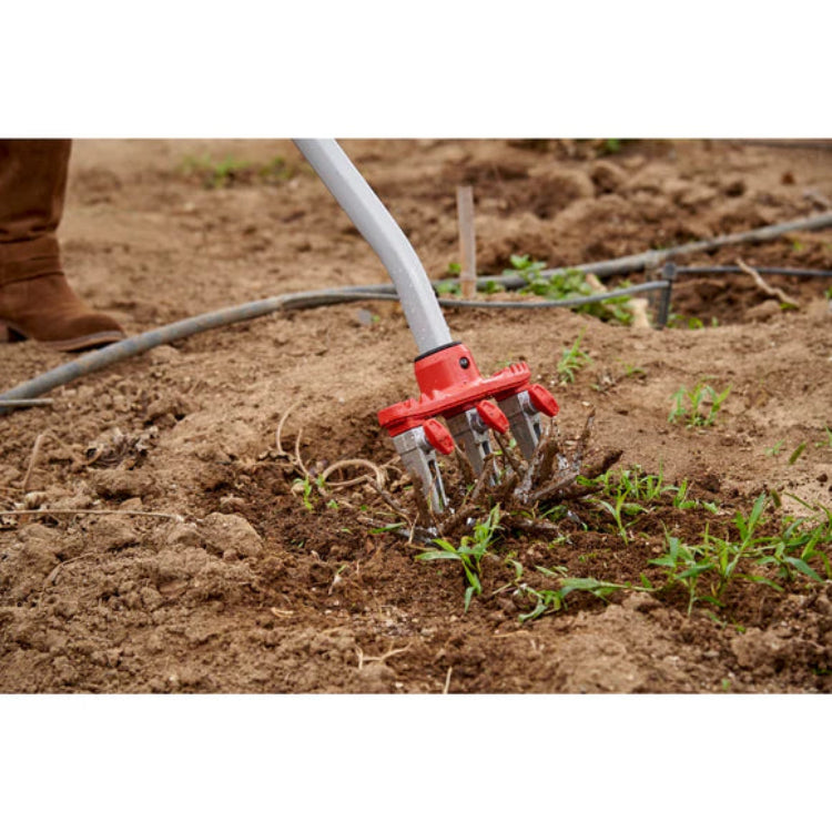 Closeup of DiscCULTIVATOR head breaking up rocky soil with weeds and irrigation lines.