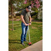 Gardener using Corona EdgeMASTER to cut a clean edge along a concrete walkway.