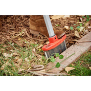 Closeup of EdgeMASTER head cutting between lawn and mulched landscape bed with leaves.