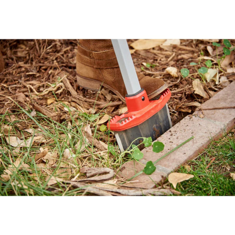 Closeup of EdgeMASTER head cutting between lawn and mulched landscape bed with leaves.