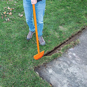 Gardener using half-moon turf edger to cut a clean edge between lawn and concrete sidewalk.