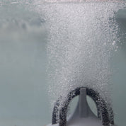 Close-up of aeration system releasing tiny bubbles into water.
