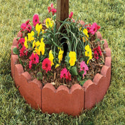 Red concrete scalloped garden edging surrounding colorful flowers and greenery.
