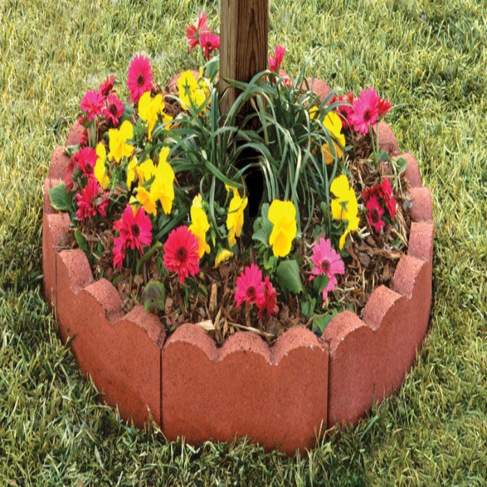 Red concrete scalloped garden edging surrounding colorful flowers and greenery.
