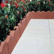 Red scalloped garden edging bordering flower bed and patio.
