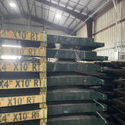 Pallet stacks of 4 inch by 10 foot green roll top edging in a warehouse storage bay.