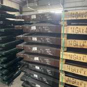 Stacks of green powder-coated 14-gauge roll top edging in 100-piece warehouse bundles.
