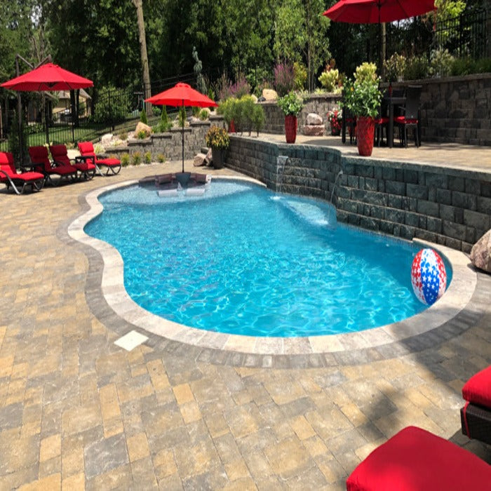 Freeform pool with stone coping, surrounded by pavers and landscaping.
