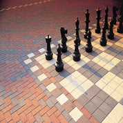 Giant outdoor chessboard on multi-colored brick pavement.
