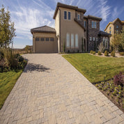 Tan paver stones driveway leading to a modern home.
