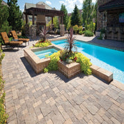 Multi-toned stone pavers surrounding a pool and spa, creating a luxurious backyard oasis.
