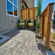 Outdoor patio with gray pavers, wooden fence, and modern seating.
