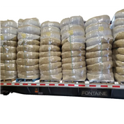 Large bales of straw wattles shrink-wrapped and secured on a flatbed trailer.
