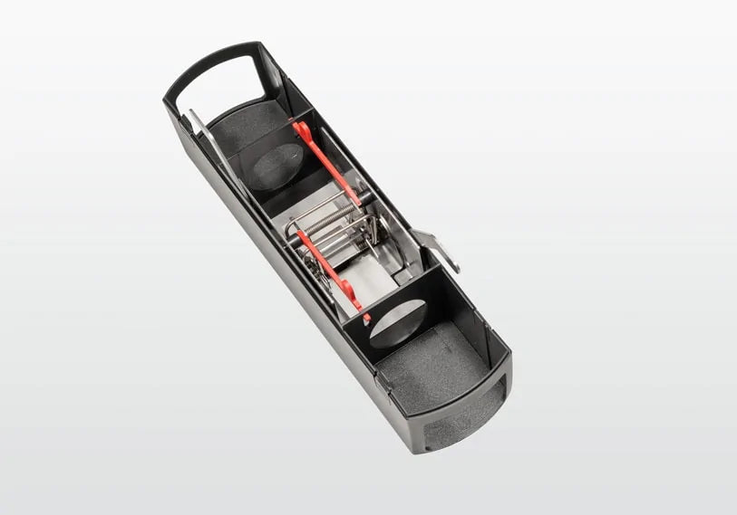 Black mouse trap with internal spring mechanism and red trigger levers, shown against a white background.
