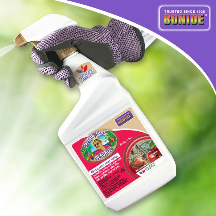 Ready-to-use organic pesticide spray bottle, shown being held with gardening gloves against a blurred green background.
