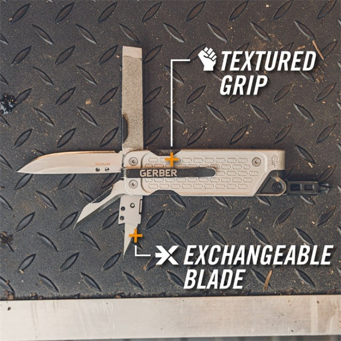 Multi-tool with interchangeable blade and textured grip, shown open on a metallic surface.
