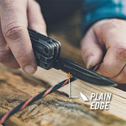 Close-up of hands using a multi-tool's knife to cut a cord outdoors.
