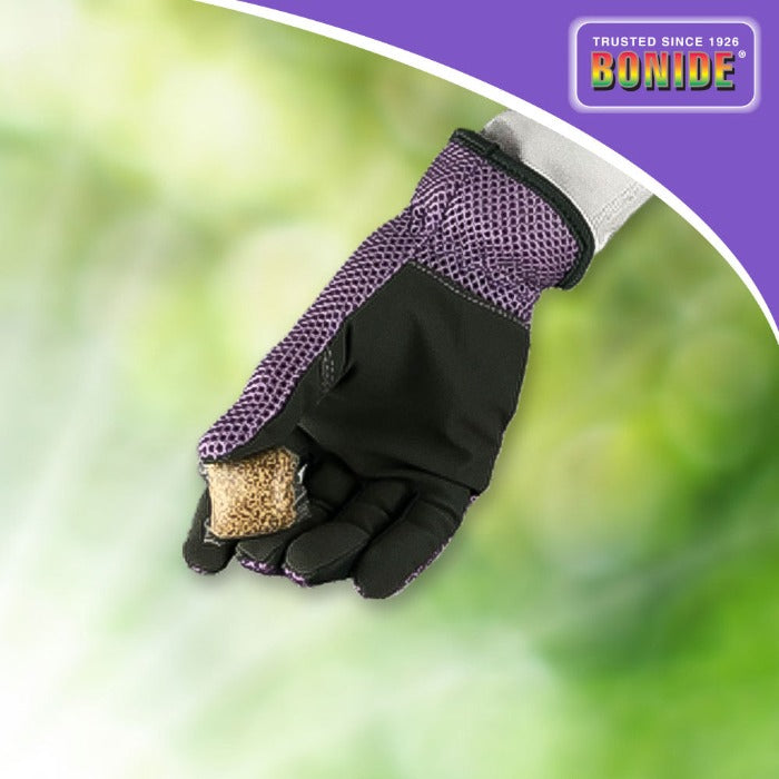 Hand in purple gardening glove holding mosquito dunks outdoors.
