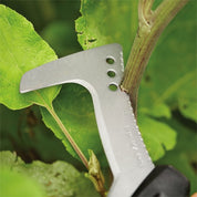 Silver billhook saw trimming a plant stem amidst lush green foliage.
