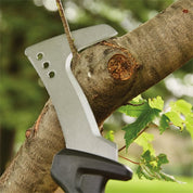 Silver billhook saw cutting a tree branch outdoors.
