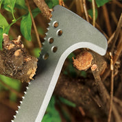 Grey metal billhook pruning branches, serrated blade detail.
