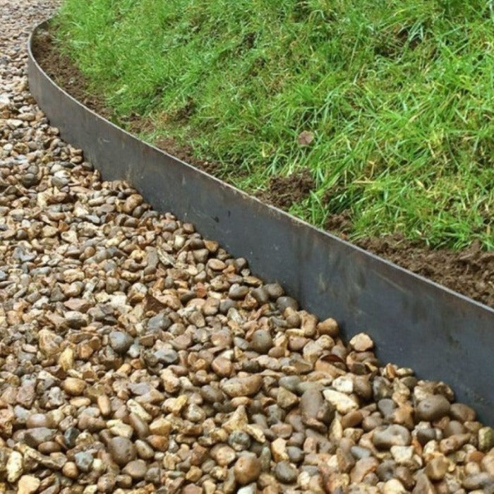 Dark metal edging installed between gravel and grass landscaping.
