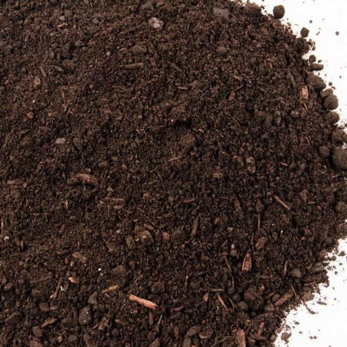 Dark brown topsoil with wood pieces, ideal for gardening.
