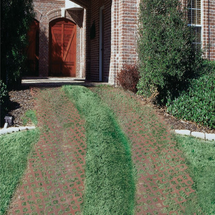 Grass-paved driveway beside a brick home, showcasing permeable paving system.

