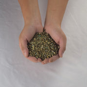 Hands cupping organic fertilizer blend; small, varied granules.
