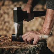 Axe being sharpened on a compact sharpener, outdoors.
