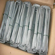 Box of galvanized metal landscape pins, bundled and ready for use.
