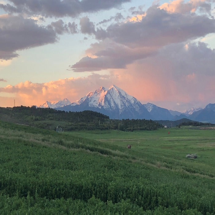 Scenic sunset over snow-capped mountains; perfect gift certificate for Colorado getaways.

