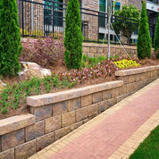 Regal Stone Pro Straight retaining wall, multi-toned brown blocks, landscaped setting.
