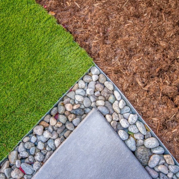 Galvanized steel edging installed between artificial turf, mulch, and stone accents.
