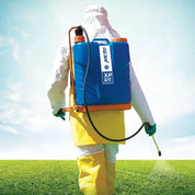 Person in protective gear applying treatment with a 3-gallon backpack sprayer in a field.
